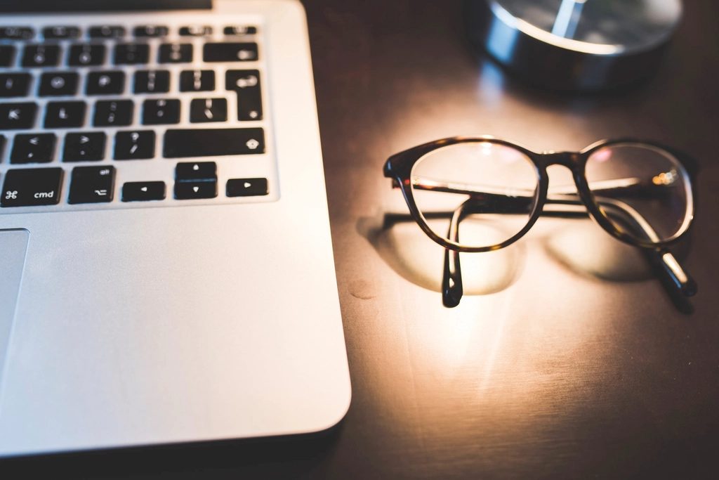 A laptop and glasses on a desk, illustrating everyday computer eyewear
