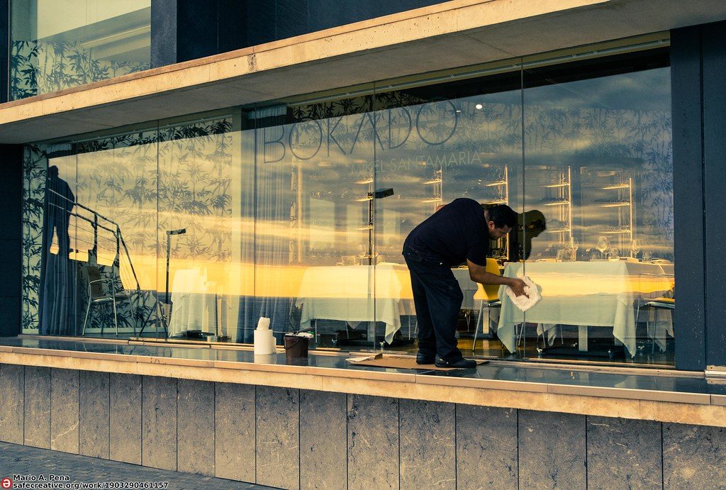 Cleaning a glass surface, illustrating careful lens and eyewear cleaning